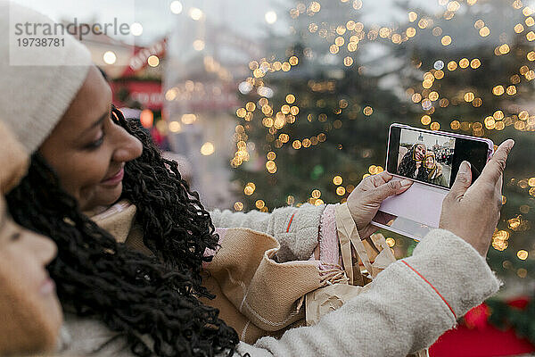Mutter macht Selfie mit Sohn per Smartphone auf dem Weihnachtsmarkt