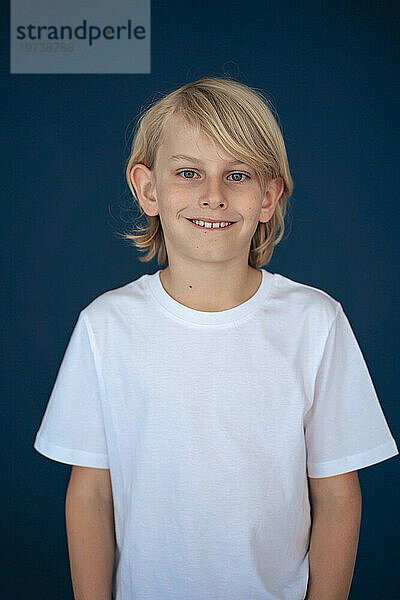 Smiling boy standing against blue background