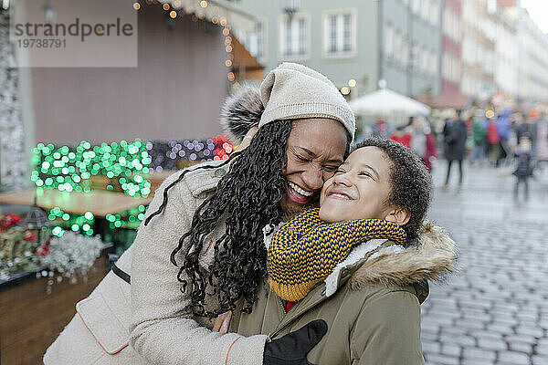 Cheerful mother hugging son at Christmas market