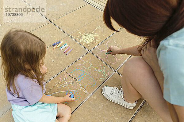 Mutter und Tochter zeichnen auf Fliesenboden im Park