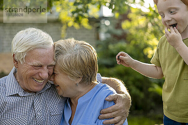 Happy elderly senior couple with grandson in garden