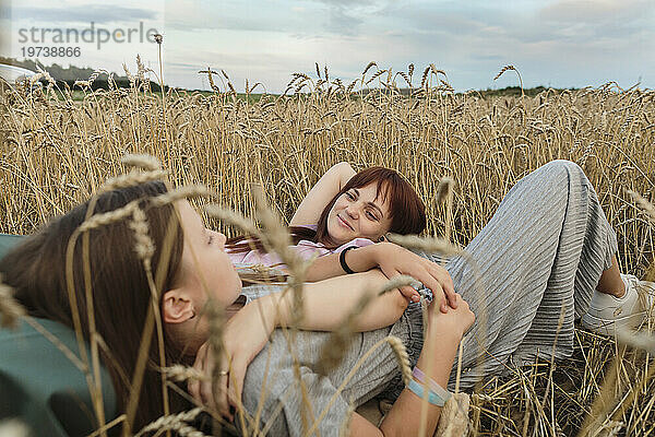 Happy mother and daughter lying in field