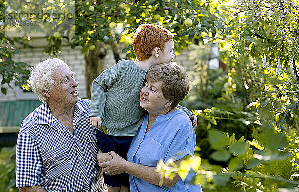 Älterer Mann und Frau mit Enkel im Garten