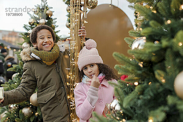 Happy brother and sister enjoying near Christmas trees at market