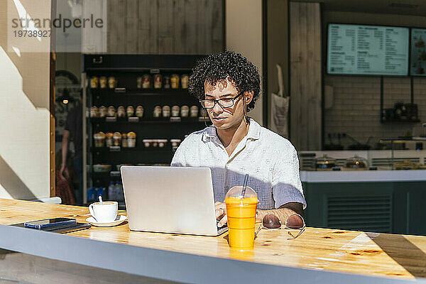 Junger Freiberufler nutzt Laptop am Tisch im Café
