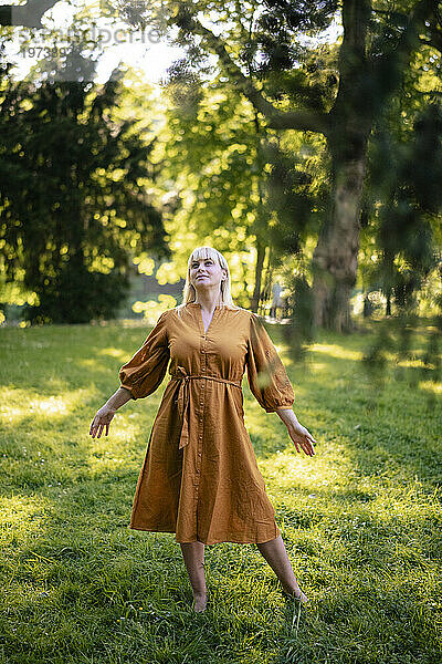 Blonde Frau steht auf Gras im Park