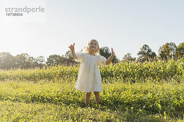 Smiling girl enjoying in front of field on sunny day