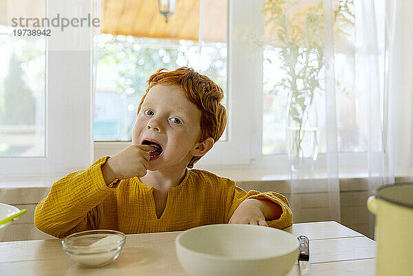 Junge isst Zucker am Tisch in der Küche