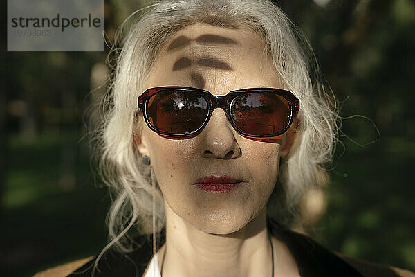 Reife Frau mit Sonnenbrille im Park