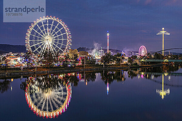Germany  Baden-Wurttemberg  Stuttgart  Cannstatter Wasen  Glowing Ferris Wheel reflecting in Neckar river at night