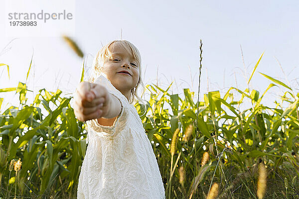 Lächelndes Mädchen hält Ernte vor Pflanzen