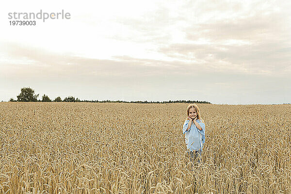 Lächelndes Mädchen  das inmitten eines Feldes unter Himmel steht