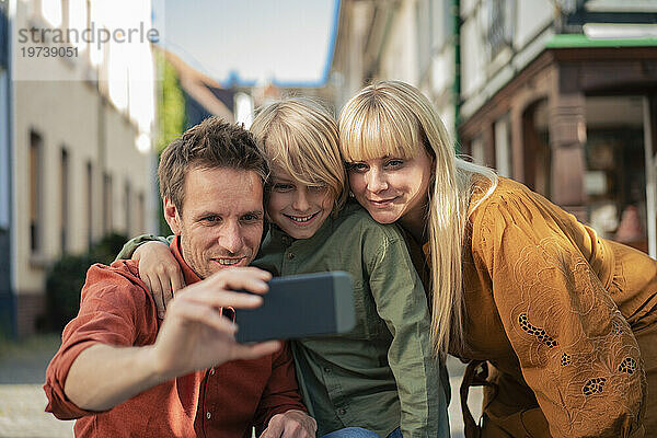 Glücklicher Vater macht Selfie mit Frau und Sohn per Smartphone