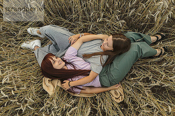 Smiling mother and daughter lying amidst field