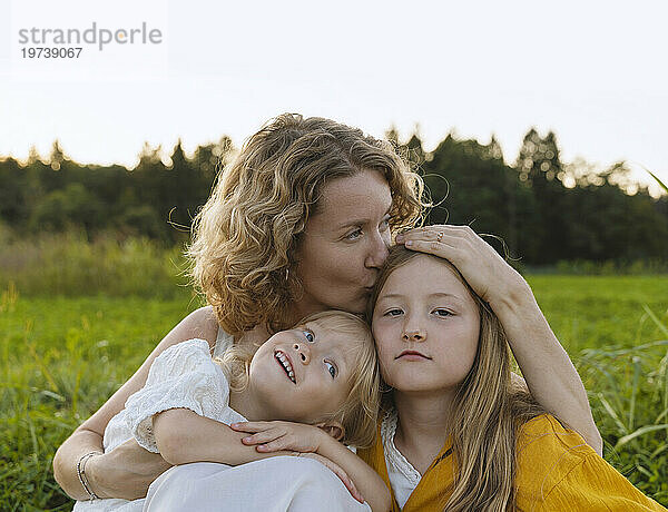 Mutter küsst und umarmt Töchter auf dem Feld