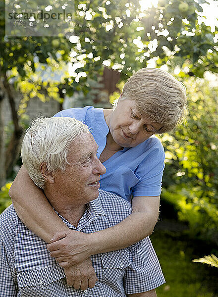 Ältere Frau umarmt Mann im Garten
