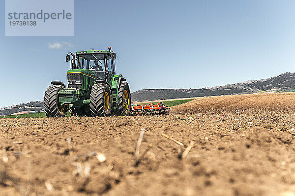 Bauer pflügt Feld mit Traktor unter Himmel