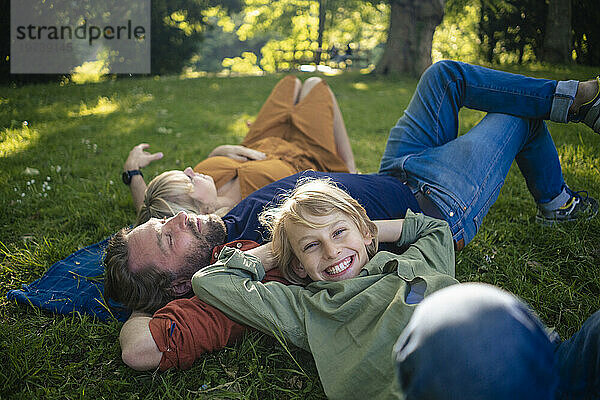 Glücklicher Junge mit Eltern  die sich im Park entspannen