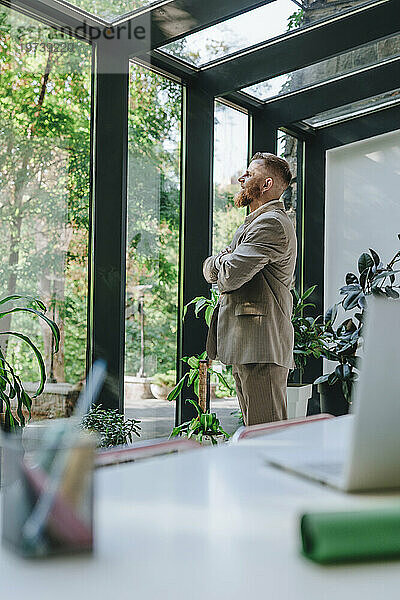 Thoughtful businessman looking through window in office