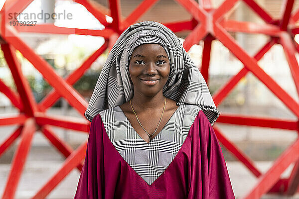 Lächelnde Frau mit Hijab vor rotem Geländer