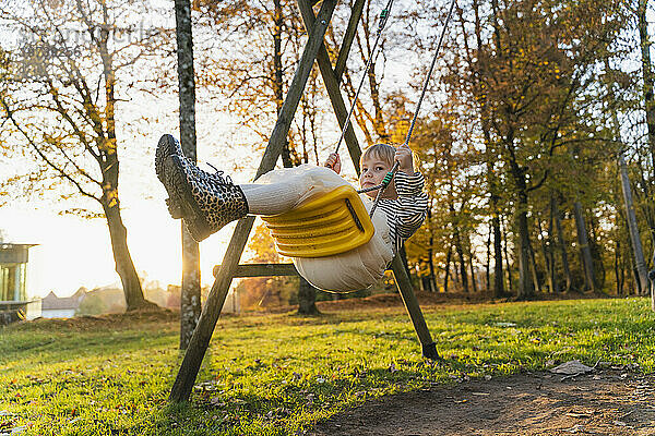 Girl swinging on swing at playground in park