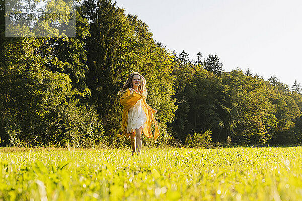 Glückliches Mädchen  das vor Bäumen auf Gras läuft