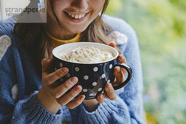 Glückliches Mädchen hält eine Tasse heiße Schokolade mit Schlagsahne