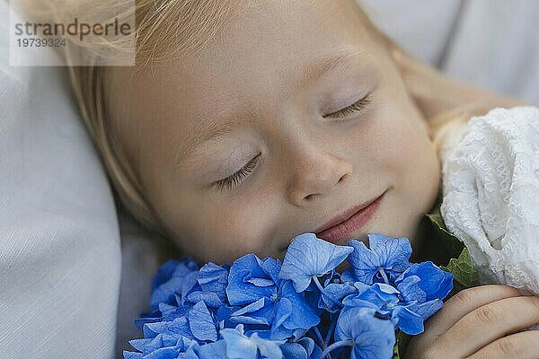 Smiling girl relaxing with blue flowers