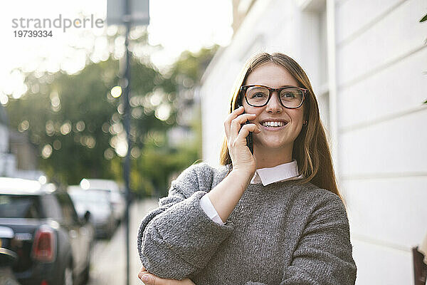 Glückliche junge Frau mit Brille  die mit dem Handy telefoniert