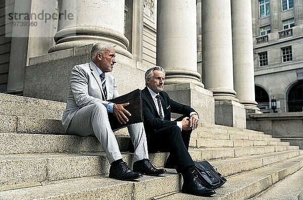 Ältere Geschäftsleute sitzen zusammen auf Stufen