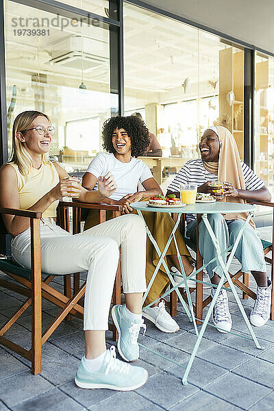 Fröhliche Freunde  die Spaß beim Essen auf dem Tisch im Straßencafé haben
