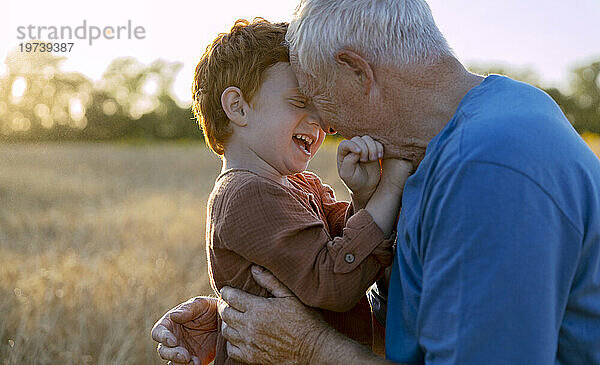 Glücklicher Großvater umarmt Enkel im landwirtschaftlichen Bereich