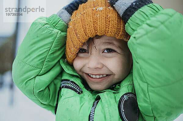 Fröhlicher Junge mit gelber Strickmütze im Winter