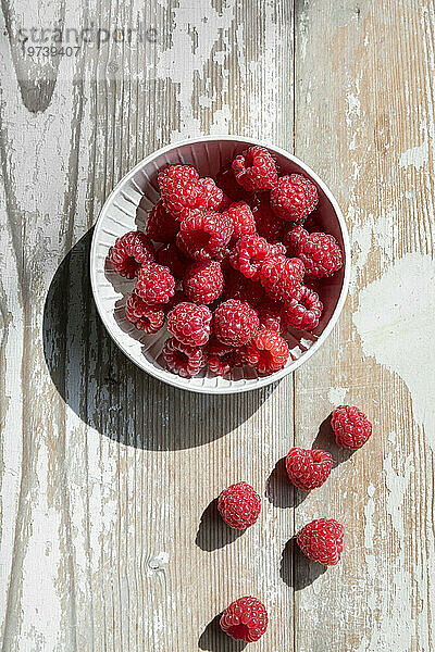 Bowl of fresh raspberries on wooden surface