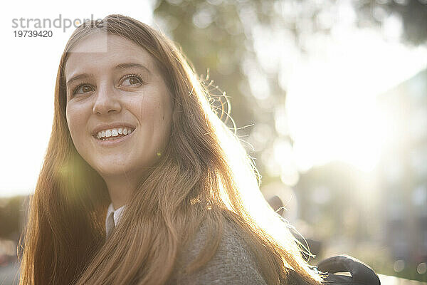Glückliche junge Frau mit langen Haaren im Sonnenlicht
