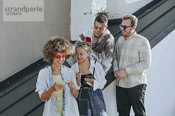 Smiling woman talking and using smart phone with friends on rooftop