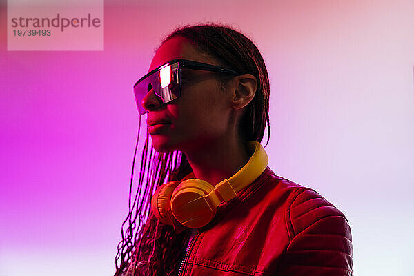 Frau mit Kopfhörern und Sonnenbrille im beleuchteten Studio