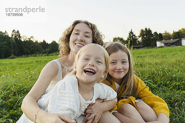 Glückliche Mutter und Töchter genießen gemeinsam im Gras