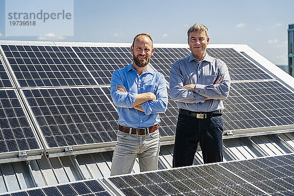 Zwei Geschäftsleute strahlen Selbstvertrauen aus  während sie zwischen Reihen von Solarpaneelen stehen und bereit sind  die Kraft der Sonne zu nutzen.