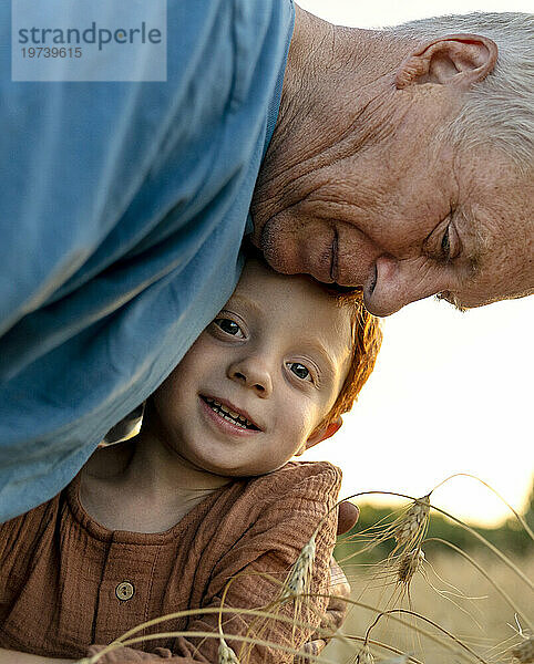 Liebevoller Großvater umarmt Enkel in der Nähe von Nutzpflanzen