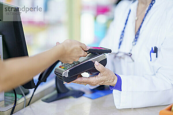 Kunde zahlt per Tap-to-Pay-Methode per Smartphone in der Apotheke