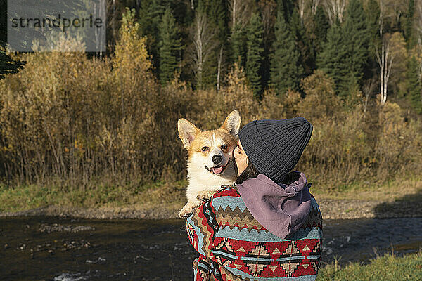 Young woman embracing Pembroke welsh corgi in park on weekend