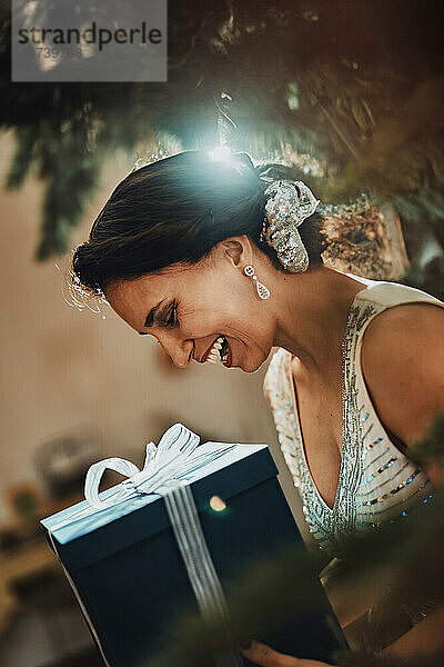 Smiling woman holding Christmas present at home