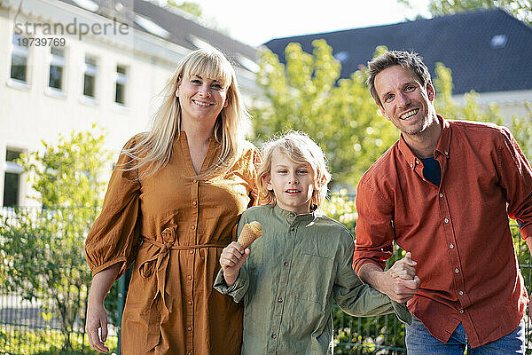 Glückliche Eltern mit ihrem Sohn  der an einem sonnigen Tag eine Eistüte hält