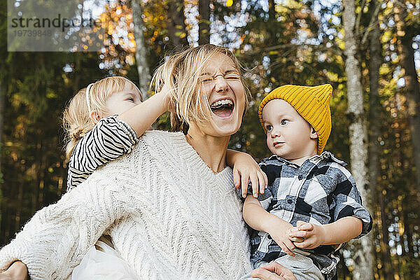 Fröhliche Mutter genießt mit Kindern im Wald