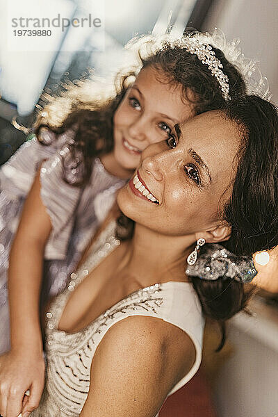 Smiling daughter wearing hairband with mother at home