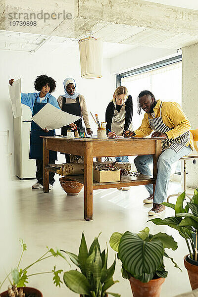 Künstler vergleichen Gemälde und arbeiten am Schreibtisch im Atelier