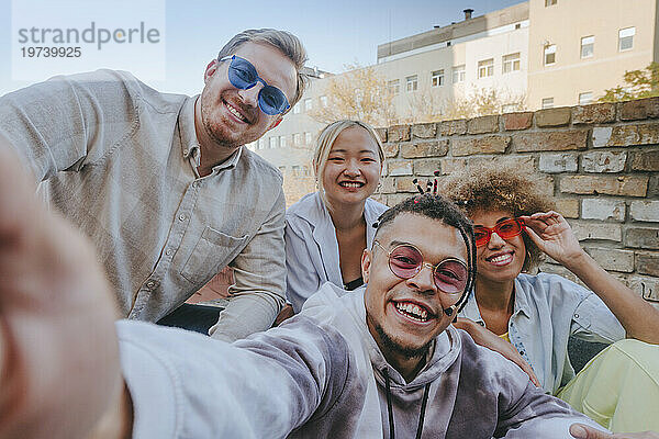 Lächelnder Mann macht Selfie mit Freunden auf dem Dach
