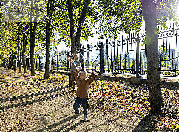 Junge jagt Seifenblasen mit Großmutter im Hintergrund im Herbstpark