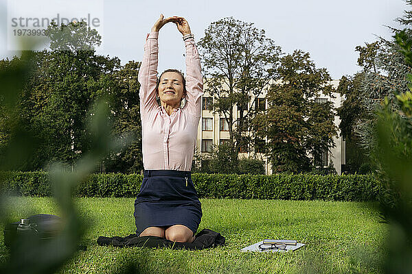 Lächelnder Freiberufler beim Yoga auf Gras im Park